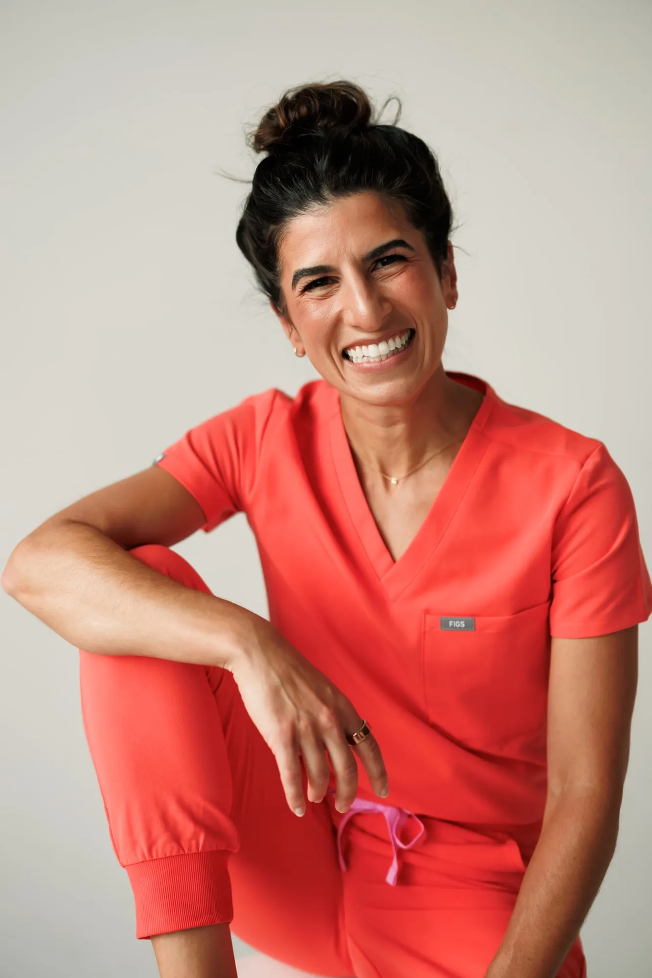 Dr. Caris Miller smiling in coral scrubs