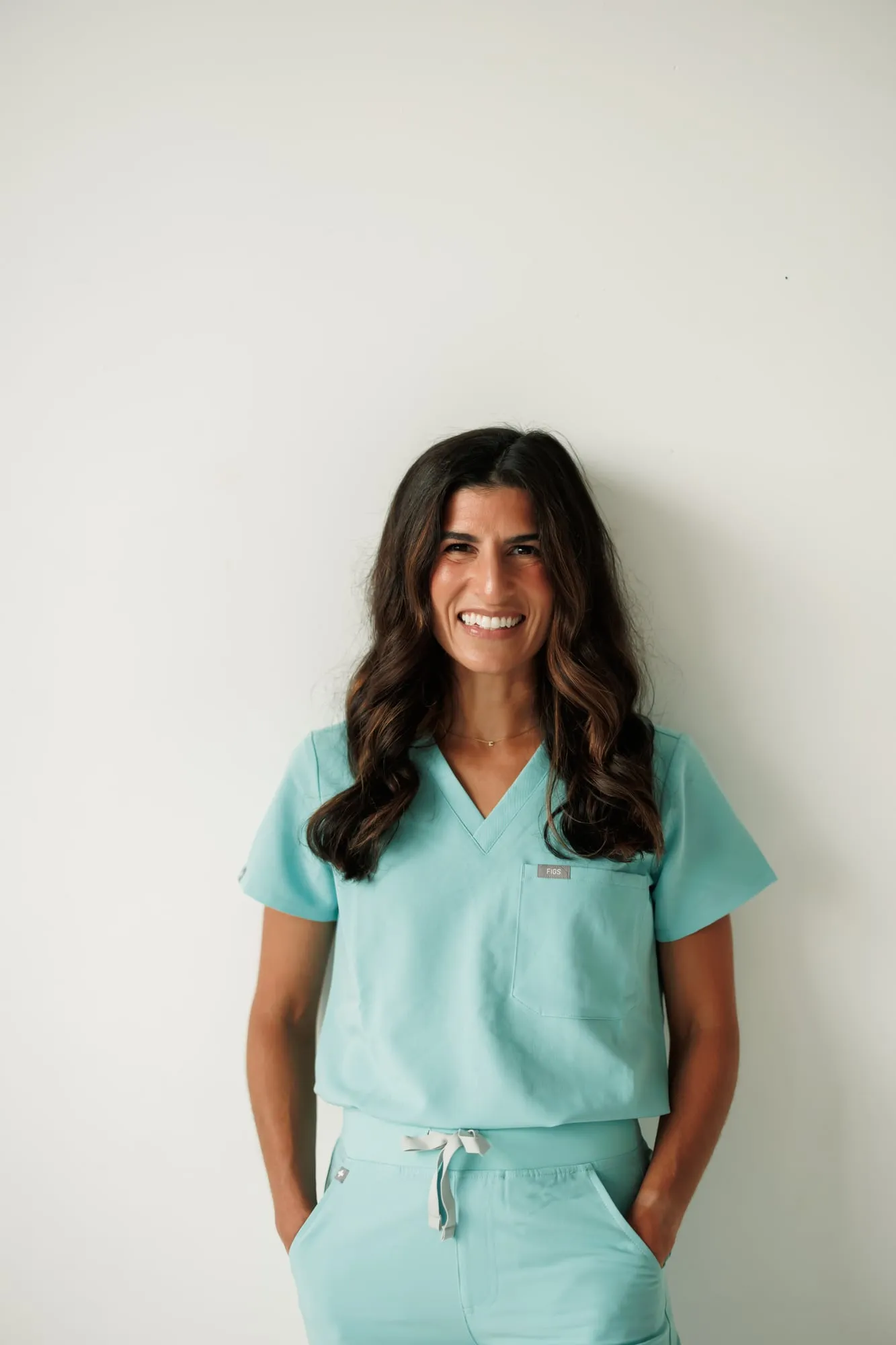 Dr. Miller in sky-blue scrubs smiling with her hands in her pockets